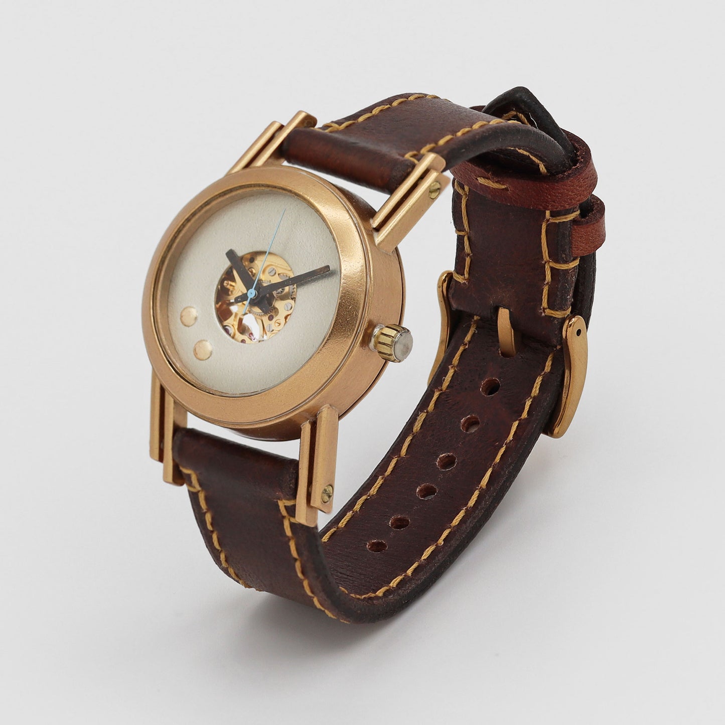 Wristwatch with brown leather strap and gold case on a light gray background