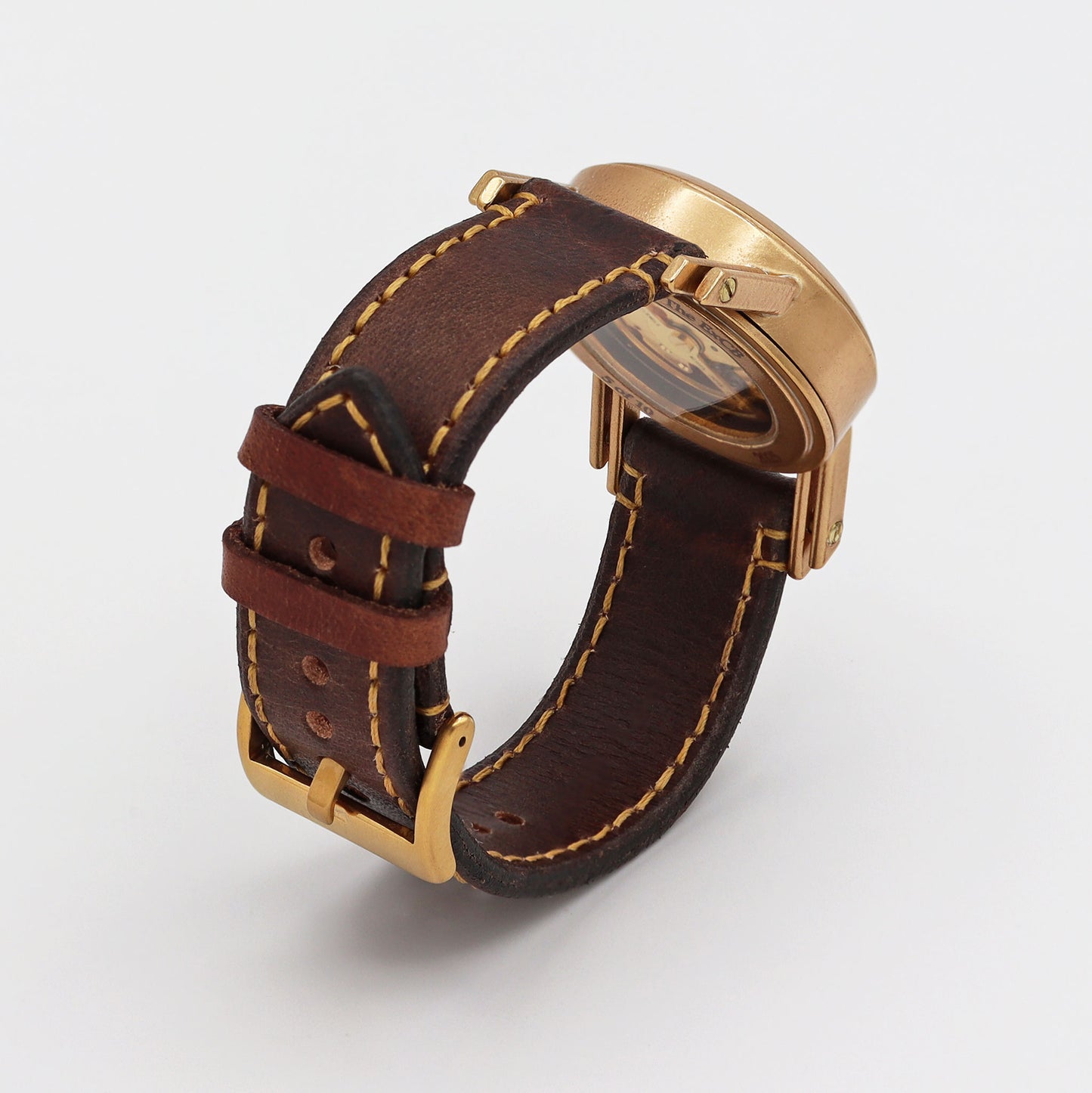 Watch with brown leather strap and bronze casing on a white background