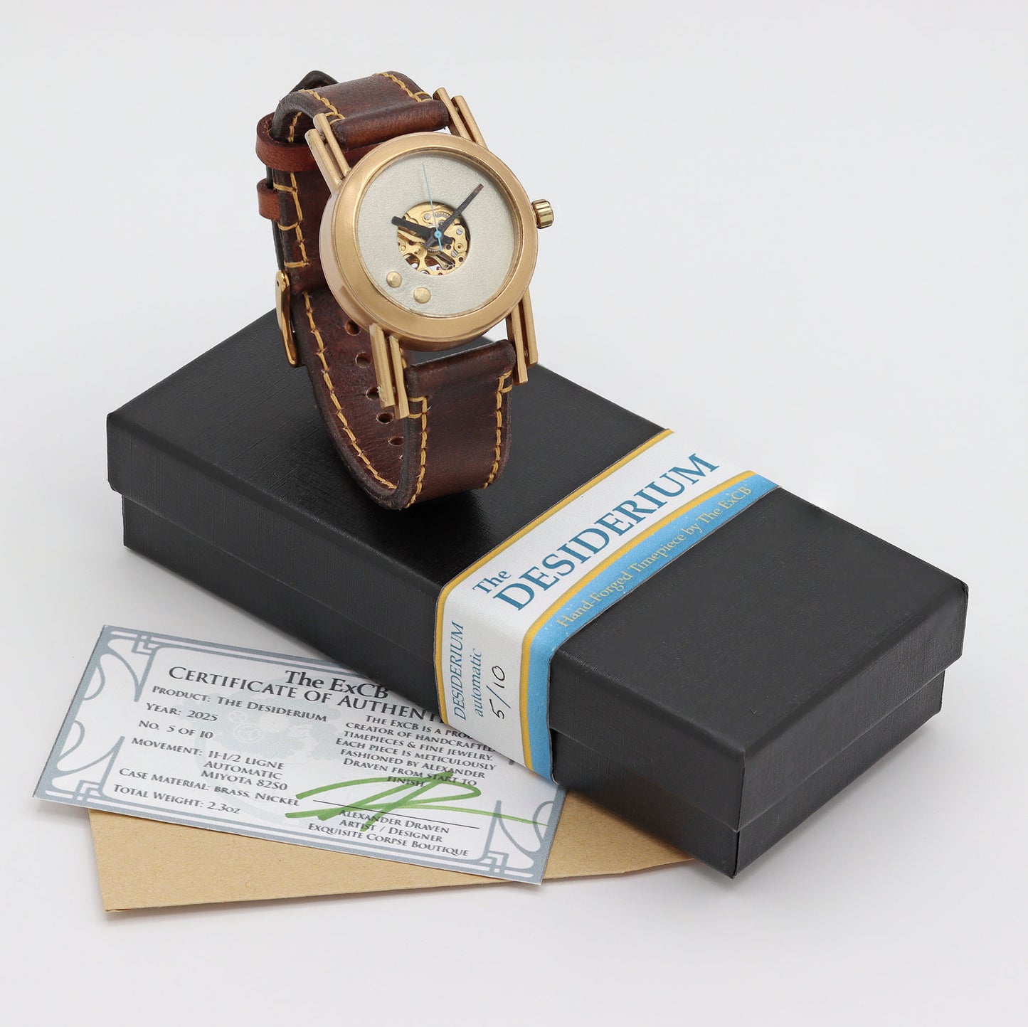 Packaging for a watch with brown leather strap and gold casing on a white background, featuring 'The Desiderium' brand.