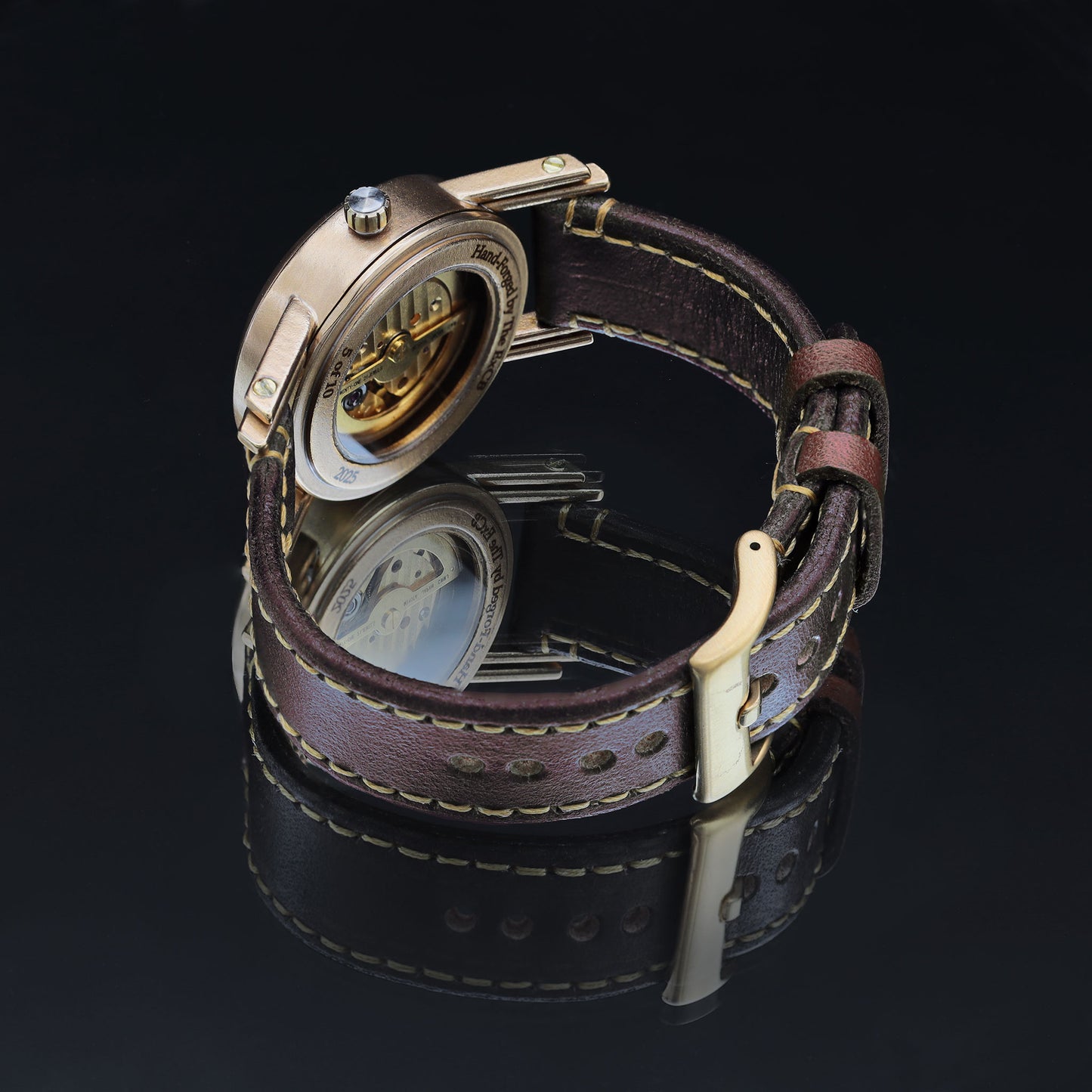 Close-up of a watch with a brown leather strap on a black background