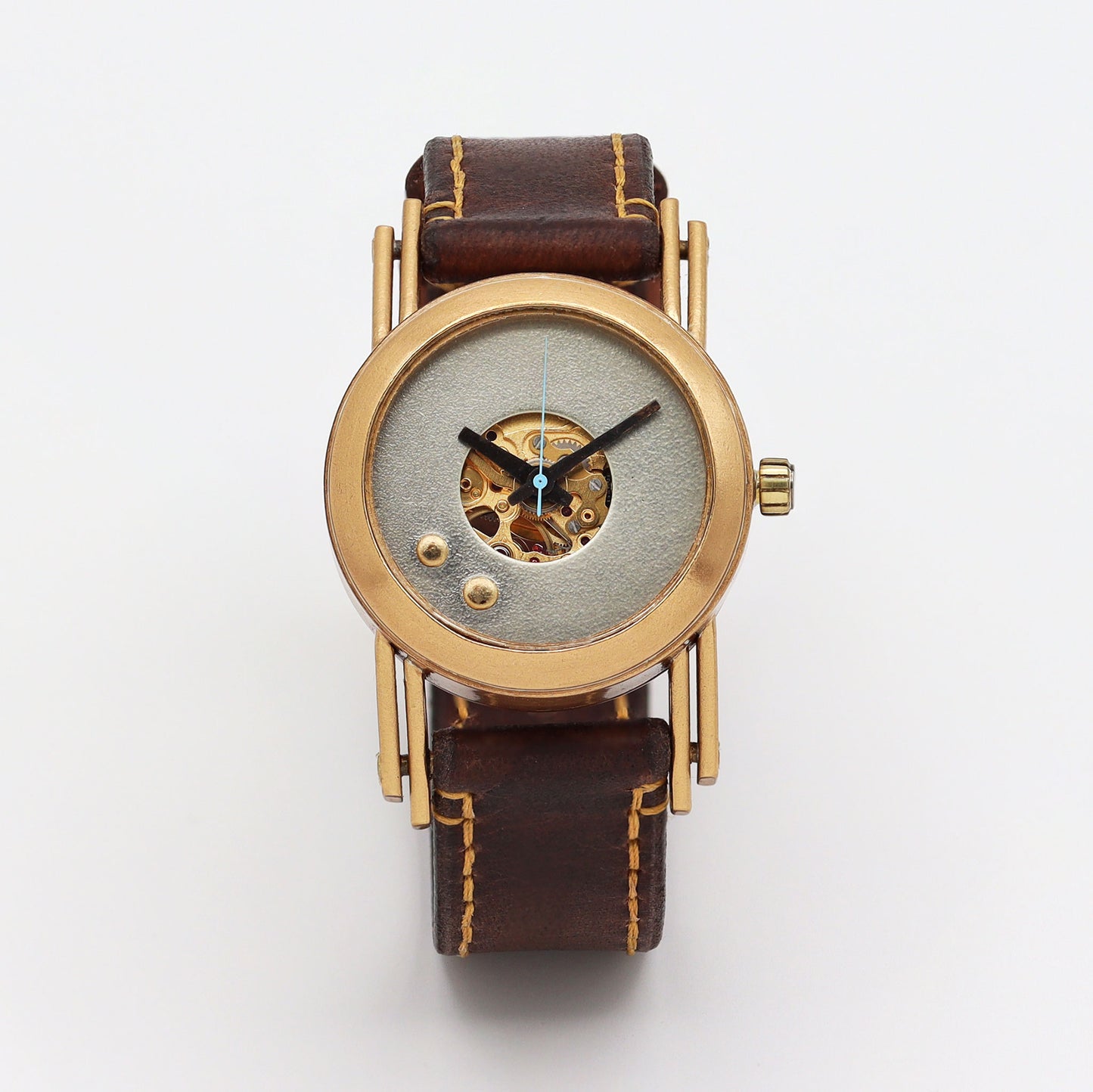 Watch with gold case and brown leather strap on a white background