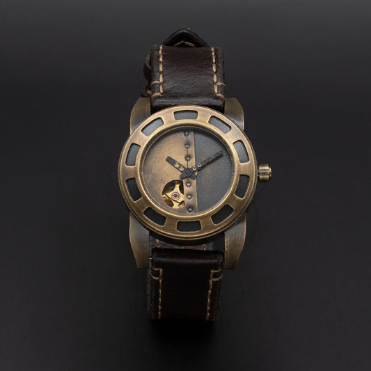 A vintage-style wristwatch with a bronze-toned metal case, skeleton dial showing a gold mechanical movement, and a dark brown leather strap with light stitching, set against a dark background.